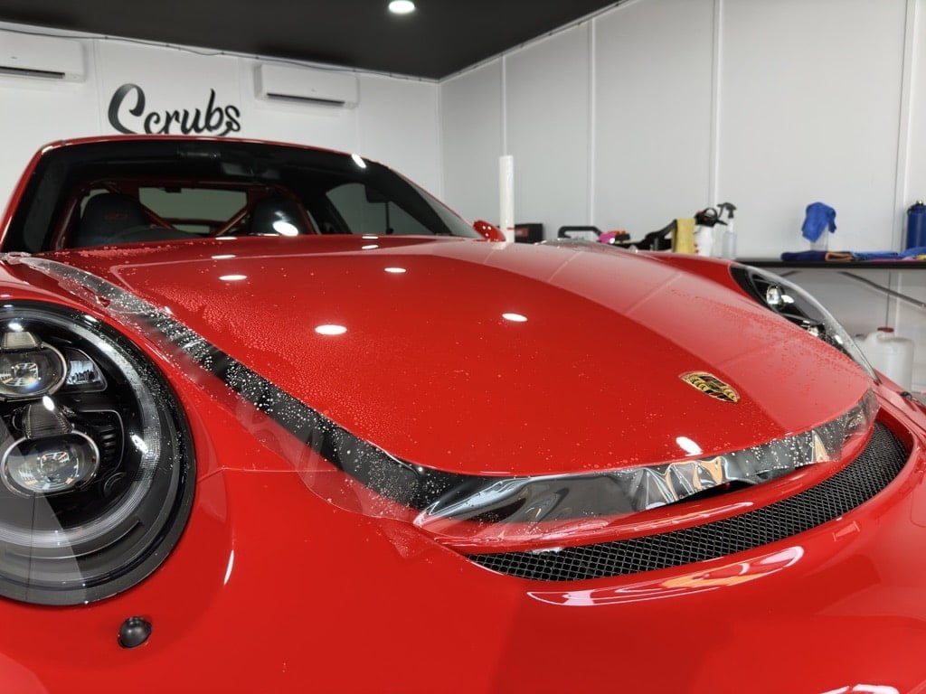 Paint protection film being installed in red Porsche