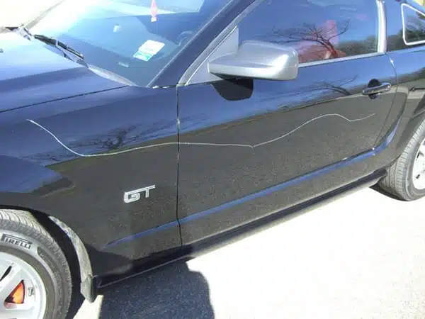 A photography of a car that has been keyed and has key marks